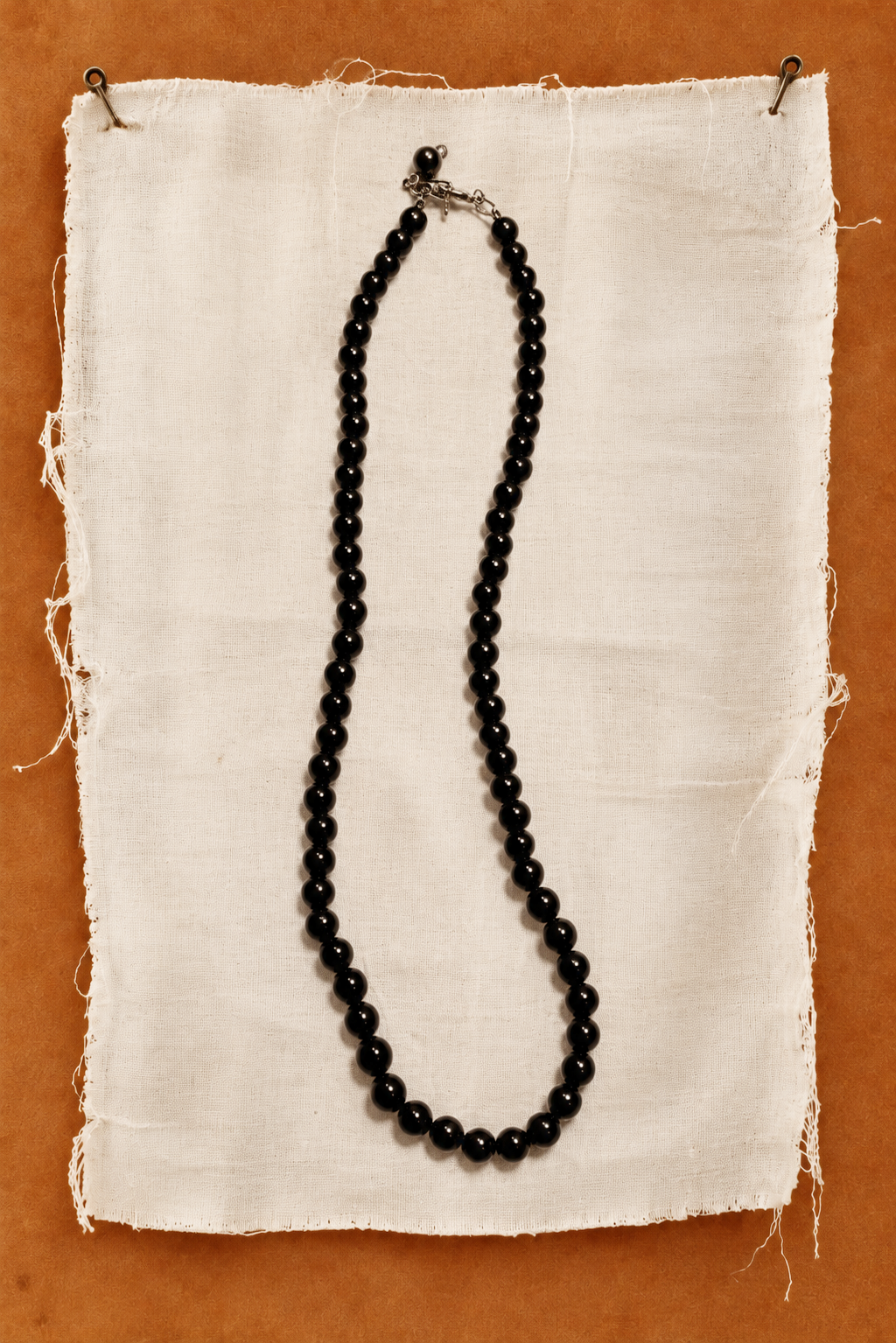 Onyx bead necklace on linen against an orange wall