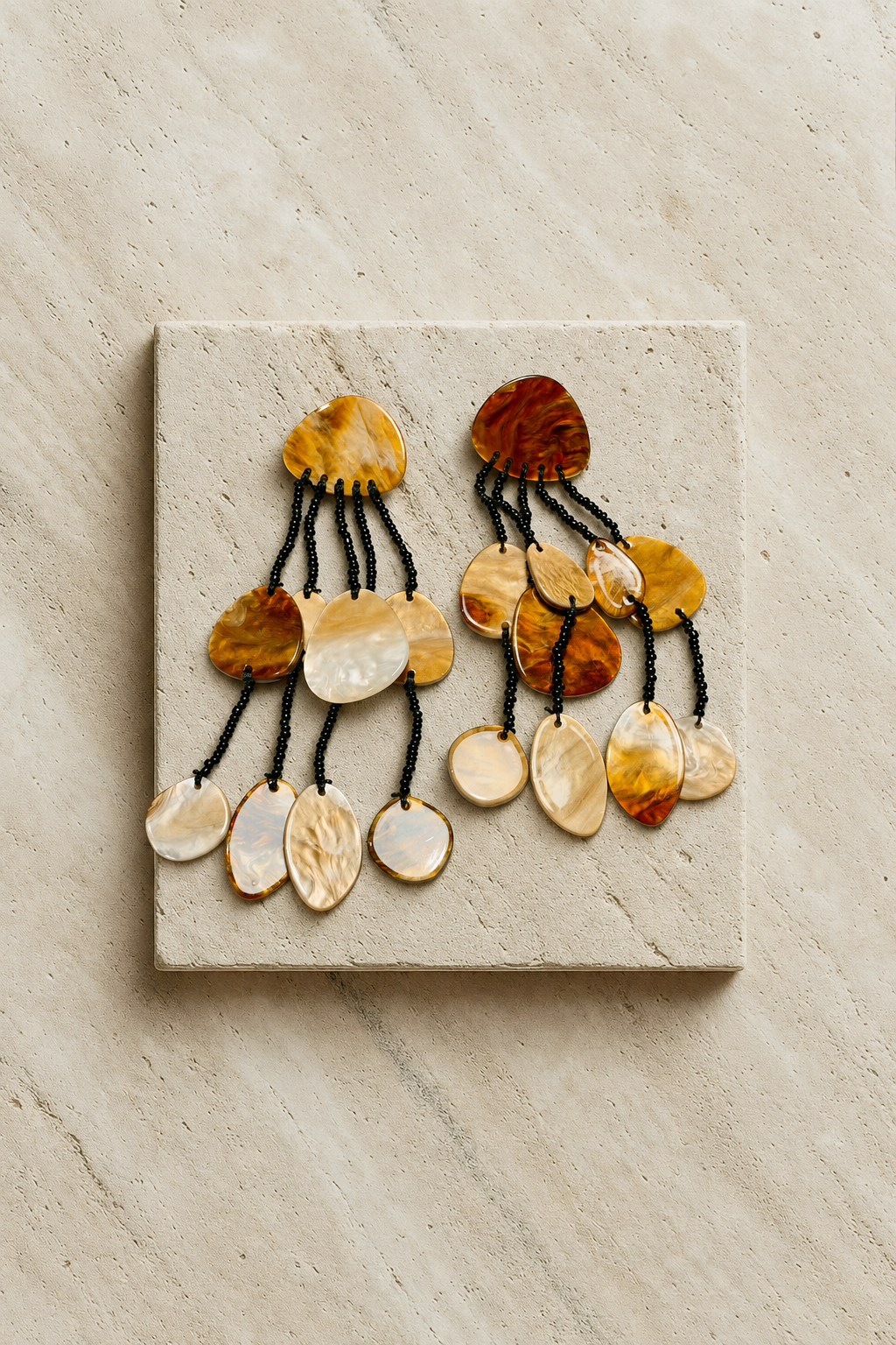 Pair of shell drop earrings on a stone tile